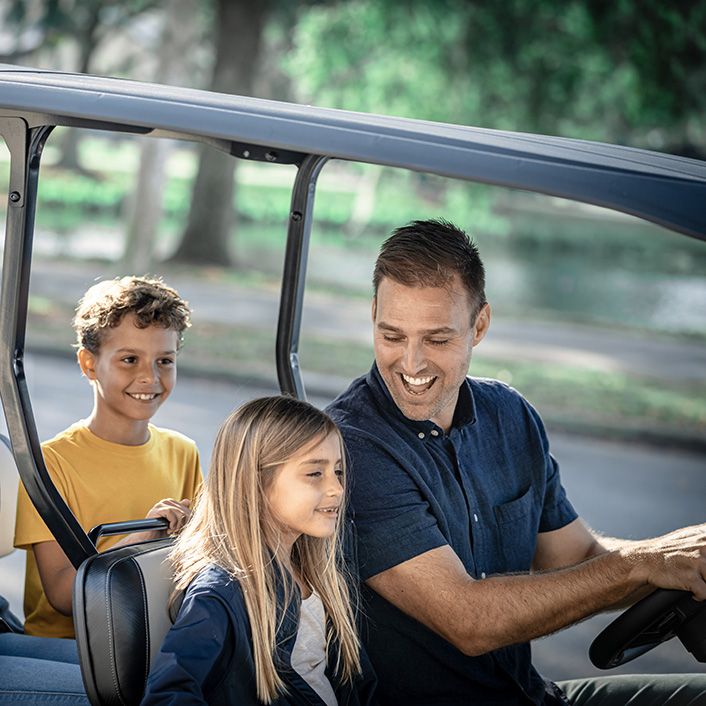 A happy family driving an E-Z-GO golf cart.