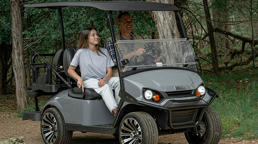 A father and daughter riding down a dirt path in an Express 4
