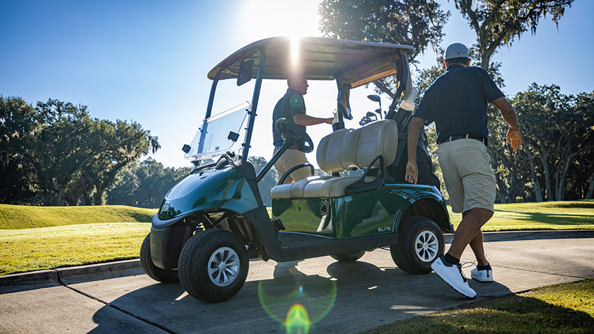 Golfers getting out of an E-Z-GO RXV on the cart path.