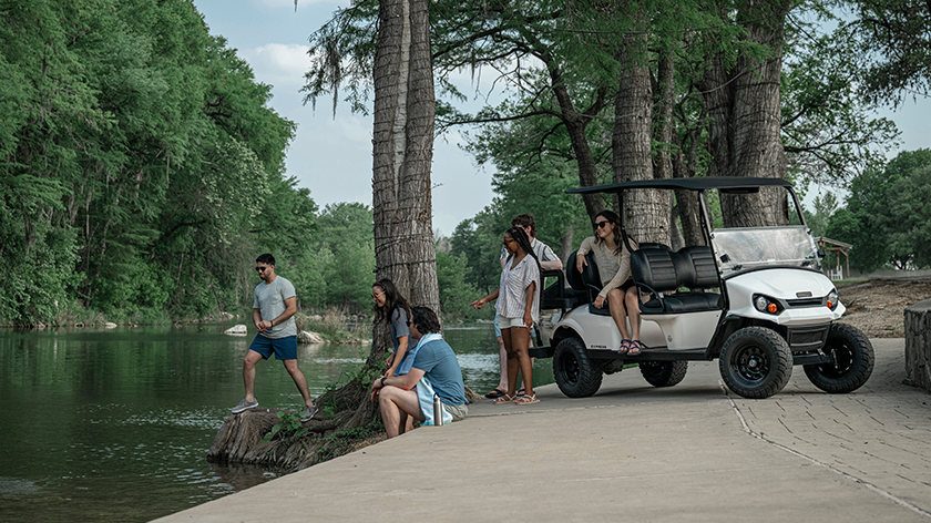 Express 6 next to the river with friends getting out of the E-Z-GO