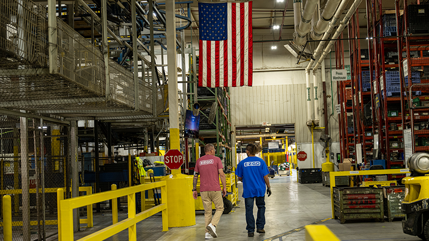 Employees walking in the E-Z-GO manufacturing building with an American Flag hanging from the ceiling.