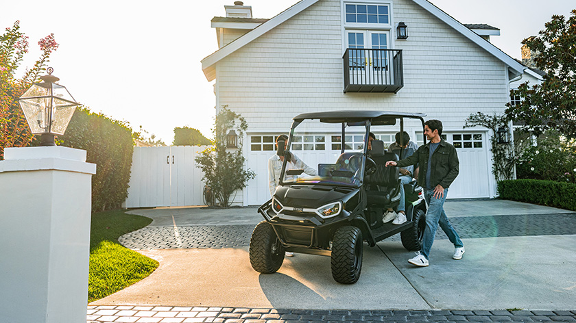 Liberty LSV in front of a house parked in the driveway with family of 4 getting in the cart.