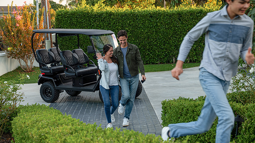 Liberty LSV parked in a driveway with family walking inside