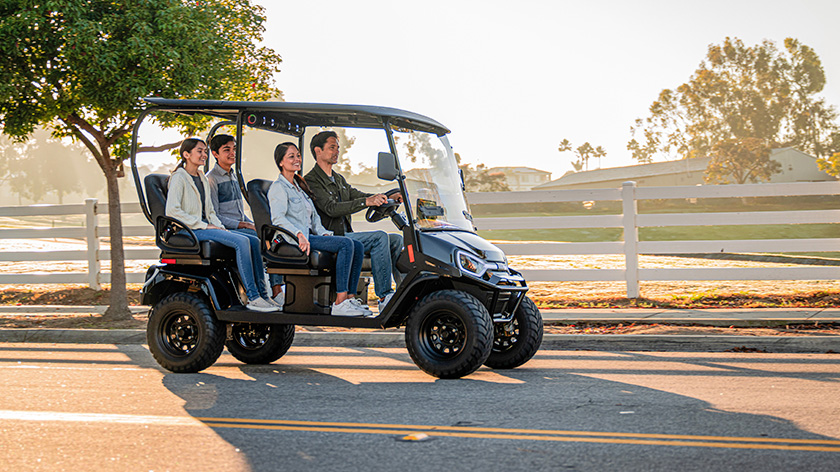 Liberty LSV Driving on a road with fence, trees, and golf course in the background