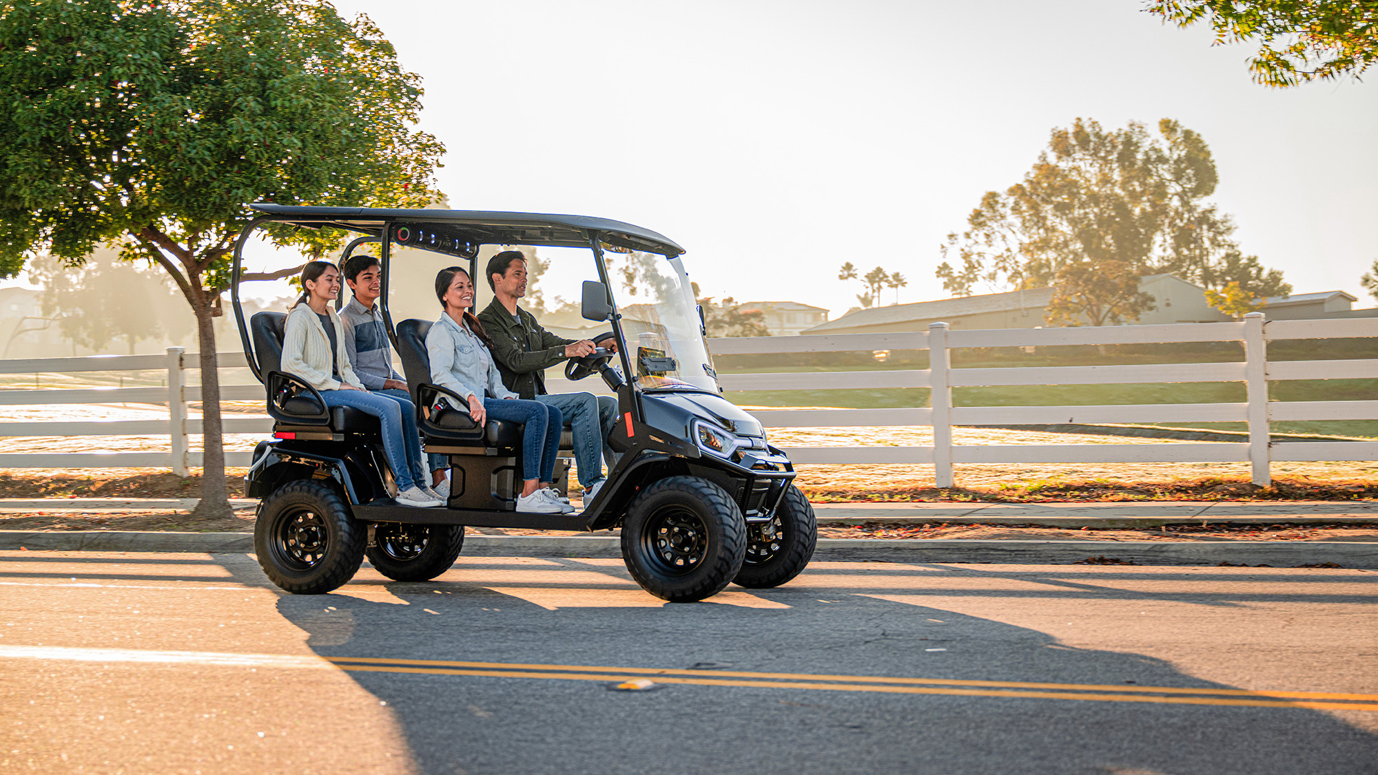 Liberty LSV Driving on a road with fence, trees, and golf course in the background