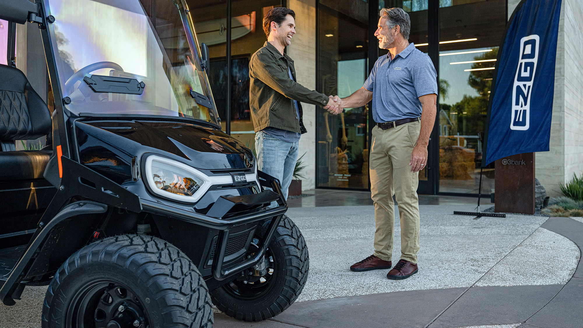 Customer in front of a golf cart dealership shaking hands with the dealer